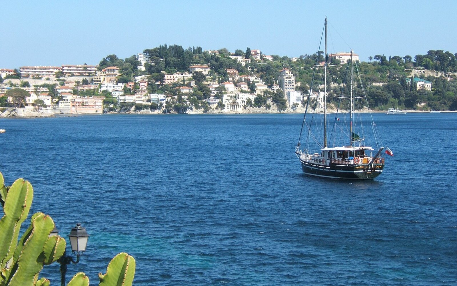 Villas above the deep blue bay of Villefranche-sur-Mer on the Côte d'Azur, with a sailing yacht at anchor