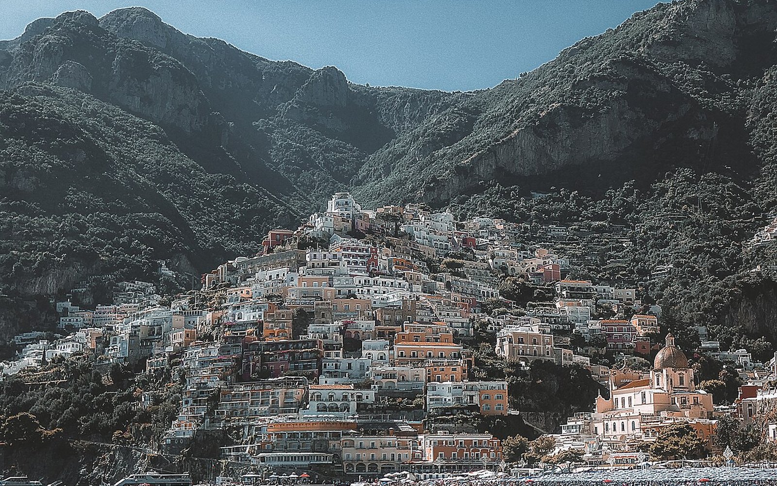Die pastellfarbenen Häuser von Positano über dem Strand an der Amalfiküste unter klarem Himmel